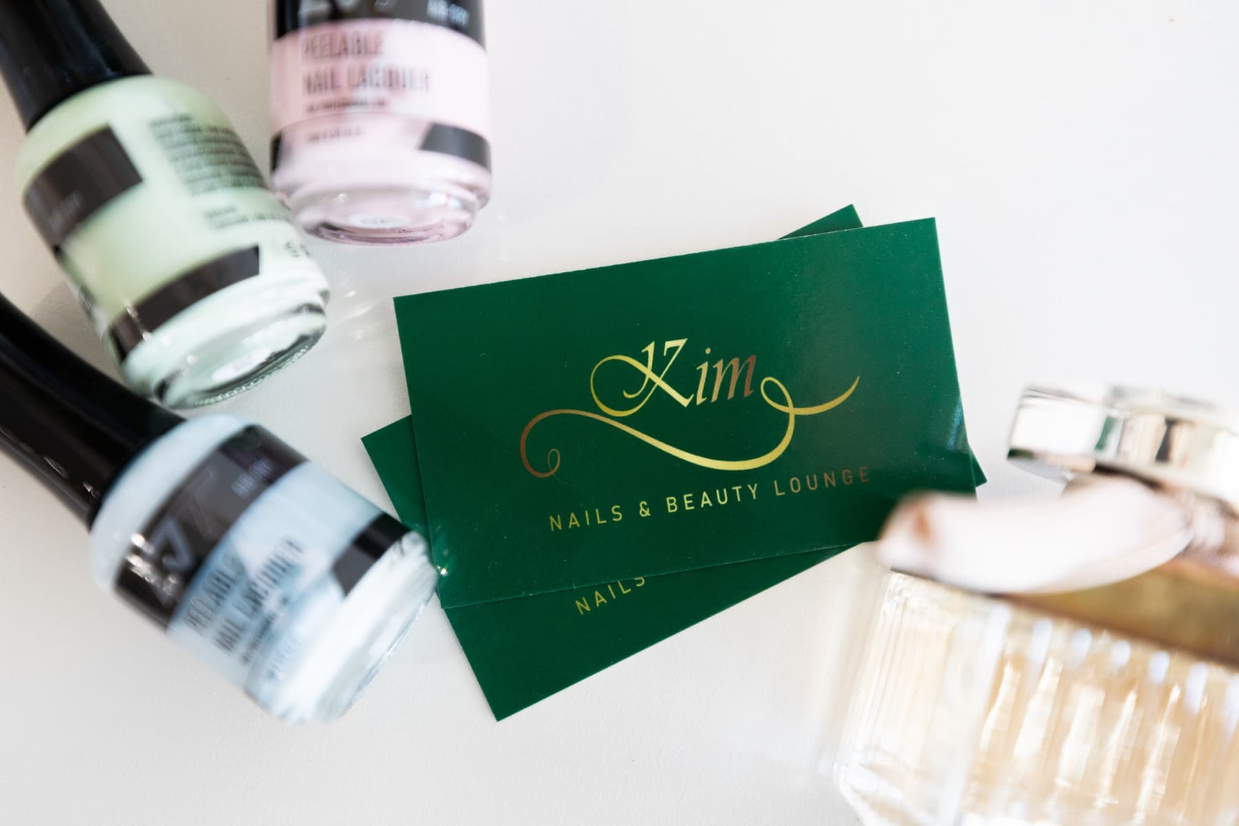 Kim Nails and Beauty Lounge business cards beside bottles of polish